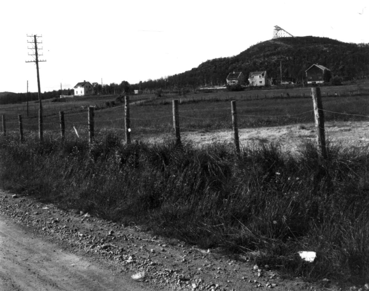 Sandnes med bebyggelse, et gjerde og en vei i forgrunnen, 1968.