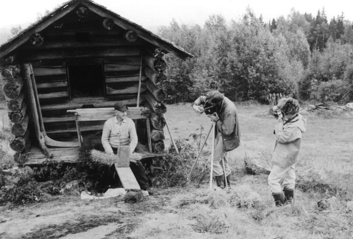 Fotograf Bjørg Disington og konservator Trond Gjerdi under filmopptak på Harstadsetra om linarbeide i september 1975. Olav Askerud sitter foran kjona og reper linfrø.