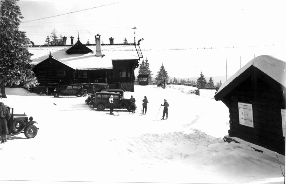 Skiløpere ved Frognerseteren, Oslo. 1934. Utenfor
restauranten står det parkerte biler