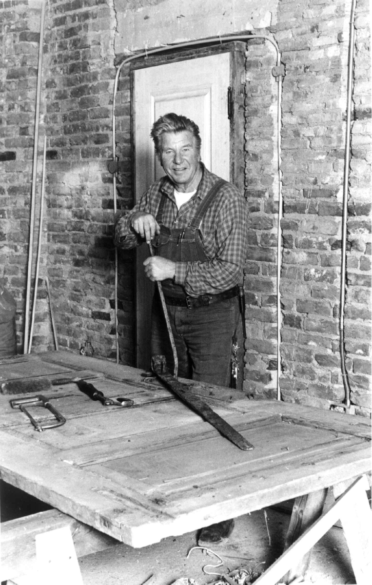 Ole G. Evensen, populært kalt pilotsnekker, siden han var tidligere pilot, som arbeidet som snekker  på Norsk Folkemuseum. Her under arbeid med en dør.