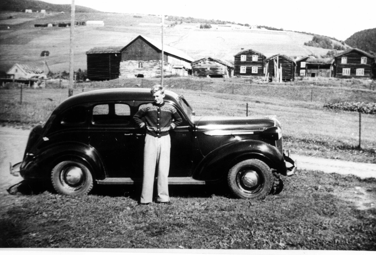 Gutt foran bil på Dovre, Oppland med gården Haugen i bakgrunnen. Fra familien Fossbergs biltur til Gudbrandsdalen.
Fra Jorunn Fossbergs familiealbum.