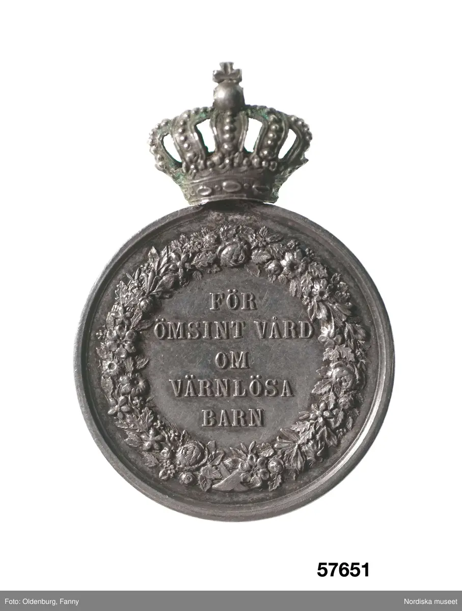 Huvudliggaren:
"Utmärkelsetecken. På åtsidan: 'FÖR ÖMSINT VÅRD OM VÄRNLÖSA BARN'. På frånsidan: 'CARL XV SVERIGES OCH NORIGES KONUNG', 'LEA AHLBORN'.
Ink.hos juden S. C. Dunér i Stockholm jämte 57.650-57.658 för [...]. Ankom 3/9 1888."