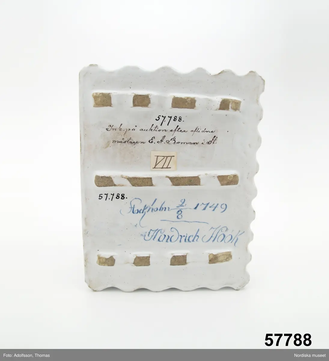 Katalogkort:
"Skrivtyg, fajans. Rektangulärt, framtill rum för pennor, upptill bläckhorn och sanddosa; dekor. med blommor och rutmönster i blått, brunt och gult, på framsidan två palmkvistar i blått, varöver H.H. 
Sign. i blått: Stockholm 2/8 1749 Hindrich Höök.
/Upmark 1904"

Skrivställ av fajans med dekor i blått och manganviolett, Rörstrand 1749.
Skrivstället med runda dosor för bläck och strösand är målat av Henrik Höök som signerat det med hela sitt namn under botten, oftast står bara målarens initialer utsatta. Han var då lärgosse vid fabriken och blev målargesäll 1754. 
Märkning: "Stockholm 2/8 1749" samt "Hindrich Höök".
Byggmäst E A Bomans samling nr  75.
/Annika Tegnér 2006