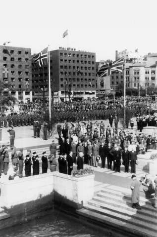 Fra Oslo under fredsdagene i 1945.
Den 13.mai kommer Kronprins Olav tilbake. Bildet viser mottagelsen på Hønnørbrygga, og Rådhusplassen med publikum, fotografer,hjemmefrontkarer og politisoldater.