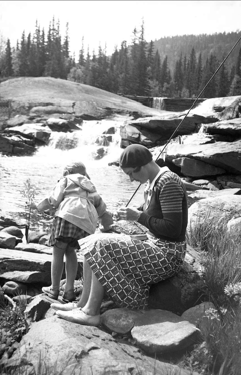 Kvinnelig venn av familien ordner med fiskeutstyr sammen med en av døtrene ved Haglebuelva 1937.