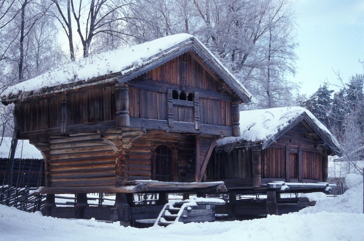 Loftet fra Tveito, bygning nummer 133 til venstre, buret fra Nedre Nisi bygning nummer 134 til høyre. Vinter og snø i Telemarkstunet på Norsk Folkemuseum.