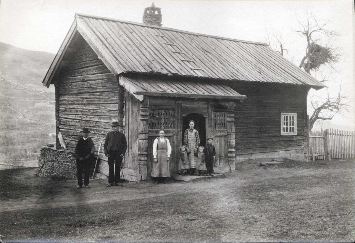 Stue, Nedre Åbø, Hjartdal, Telemark. Familie stående foran stuen.  Fotografert 1915.