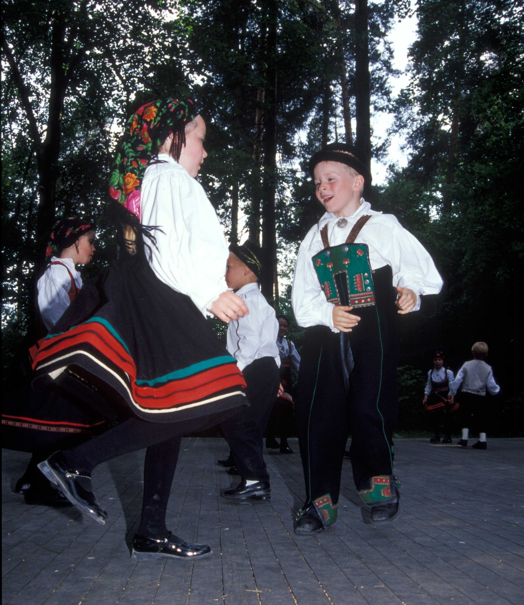 Norsk Folkemuseums dansegruppe, kledd i folkedrakter, danser folkedans i friluftsteateret NF 349. Et av parene i forgrunnen.