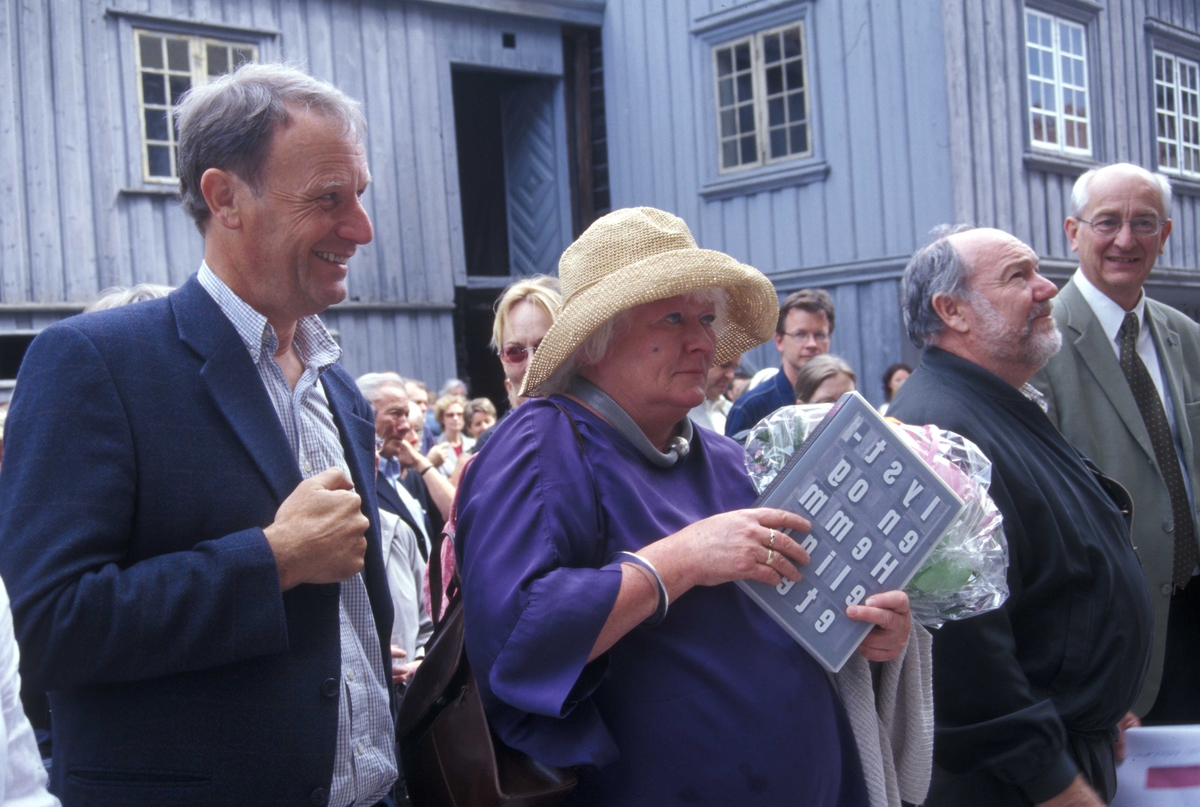 Åpningen av utstillingen "Bonytthjemmet" i OBOS-gården, Wessels gate 15, bygning nummer 234 på Norsk Folkemuseum. Direktør Olav Aaraas sammen med tidligere beboer Tove Kvalstad og andre gjester ute i friluftsmuseet. Her med Barthegården, bygning nummer 229 i bakgrunnen.