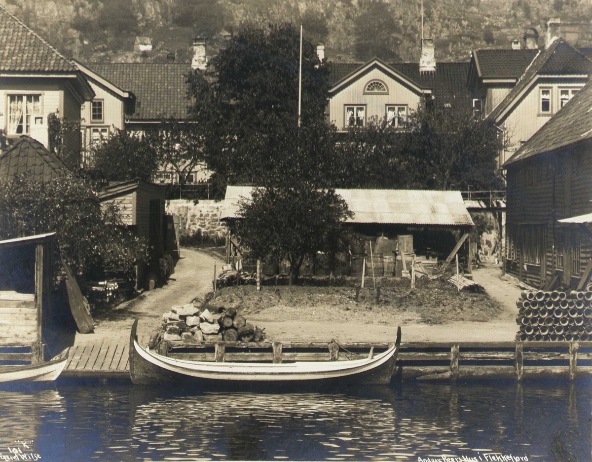 Anders Beers hus sett fra sjøsiden, Flekkefjord, Vest-Agder. Diverse boder i forgrunnen. Fotografert 1912.