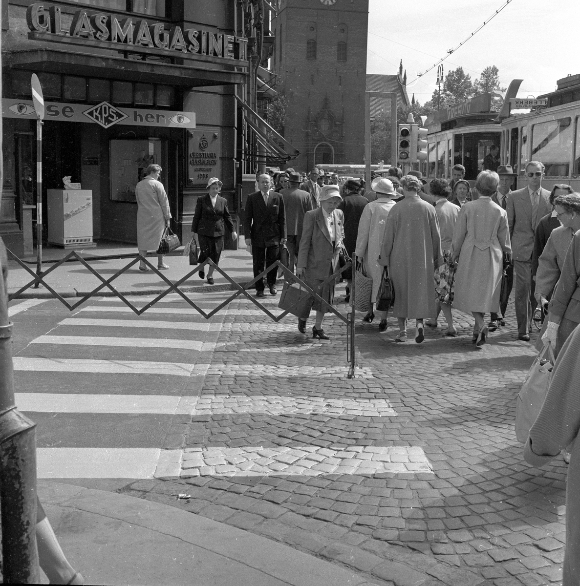 Fotgjengere går utenom nymalt fotgjengerfelt i krysset Møllergata og Stortorvet ved Glasmagasinet, Oslo. Fotografert mai 1959.