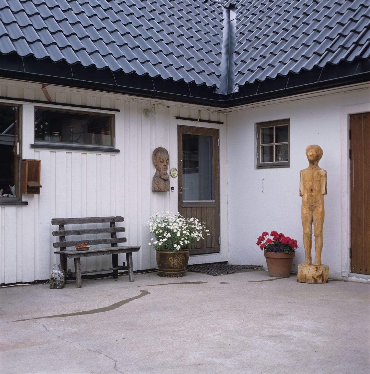 Enebolig med atelier, gårdsplass, skulptur ved veggen.  Illustrasjonsbilde fra Nye Bonytt 1989.