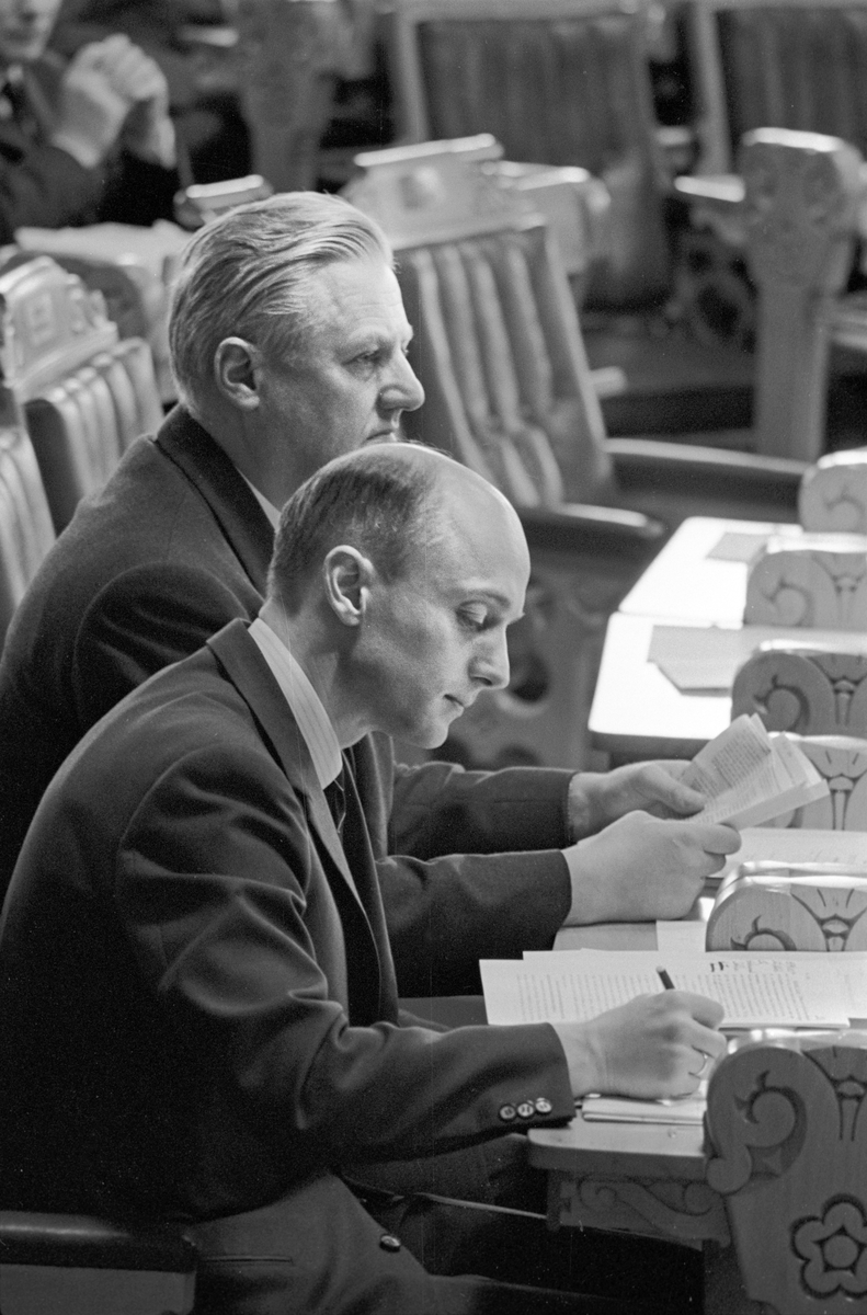 Serie. Debatt i Stortinget. Kåre Willoch og John Lyng leser dokumenter og en kvinne snakker med en politiker. Fotografert våren 1967.