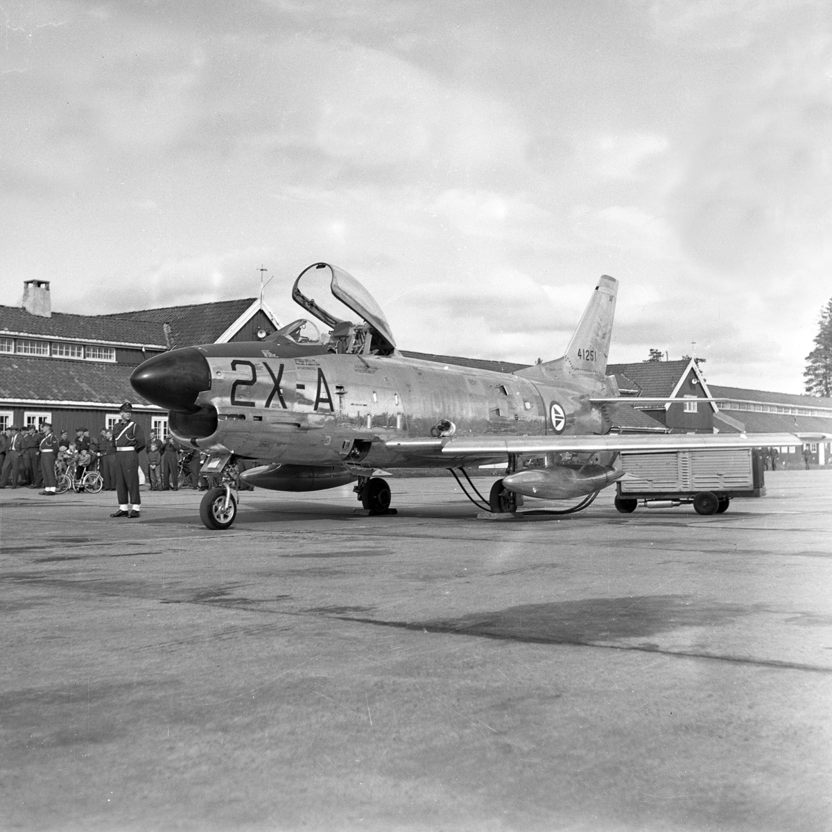 Serie. Mange uniformskledde personer er samlet i anledningen at et jagerfly skal bryte lydmuren. Jagerpiloten sitter i flyet. Fotografert 12. og 13. september 1955.