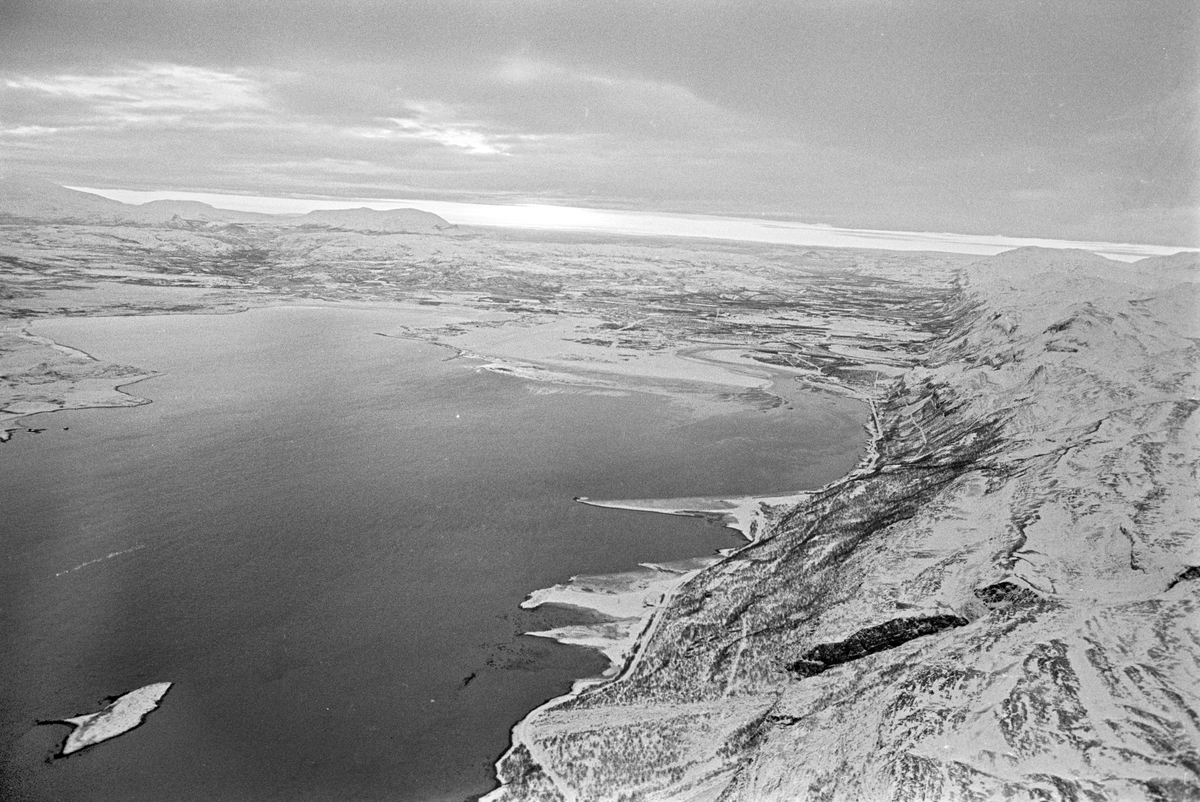 Serie. Ombord på SAS flyet til Tromsø. Flyfoto over snødekkete fjell. To flyvere i flytårnet. To menn og en kvinne, ant. Eva Lie, sitter rundt et bord. Fotografert desember 1965. 