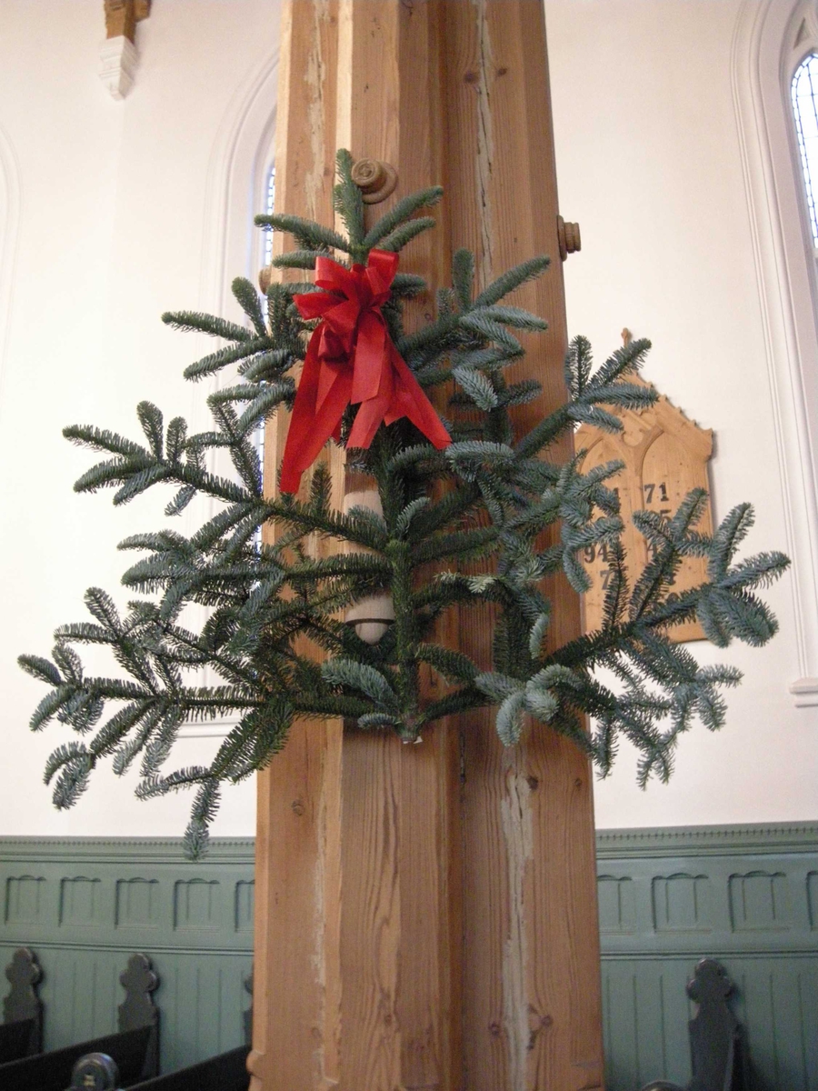 1. juledag i Kristiansand Domkirke, 25.12.2007. Grener med granbar pyntet med røde sløyfer henger på stolpene i kirken.