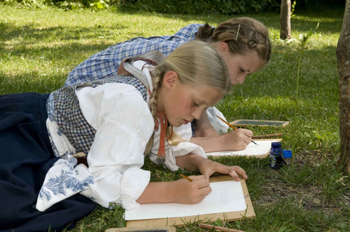 Ferieskolen uke 27, 2009.
Undervisning foregår utendørs, barna lærer å skrive med blekk.
