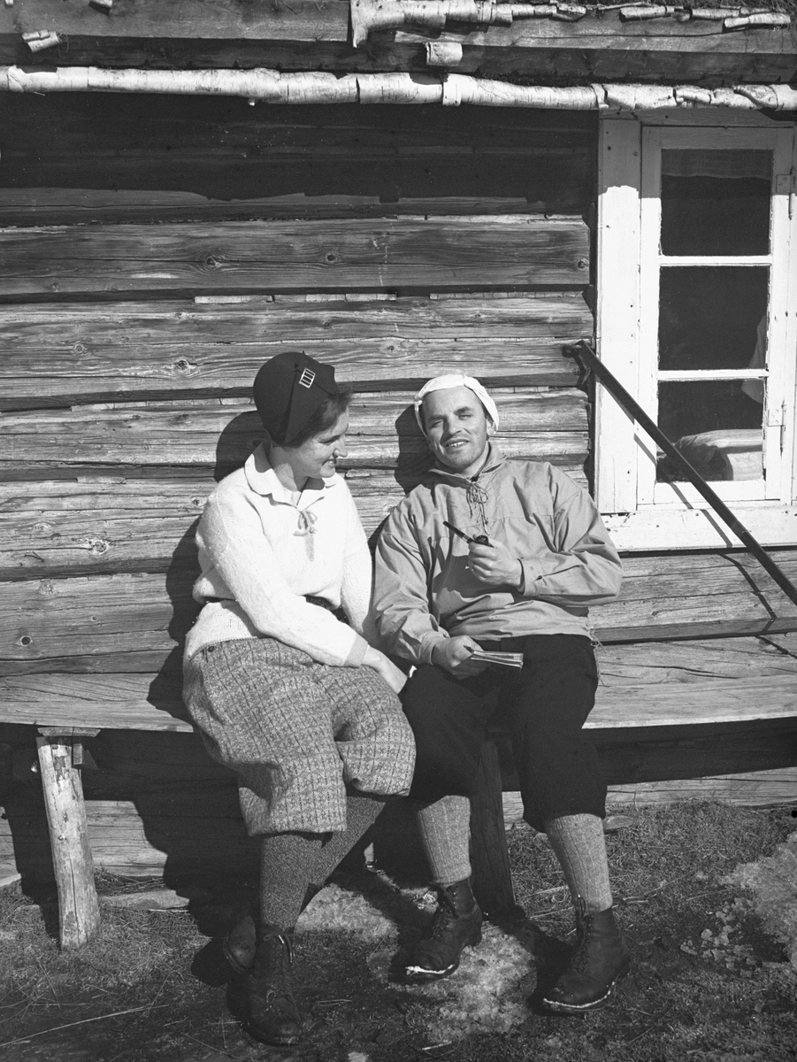 Dordi og Fritjof Arentz sitter hytteveggen og soler seg.  Fotografert påsken 1932.