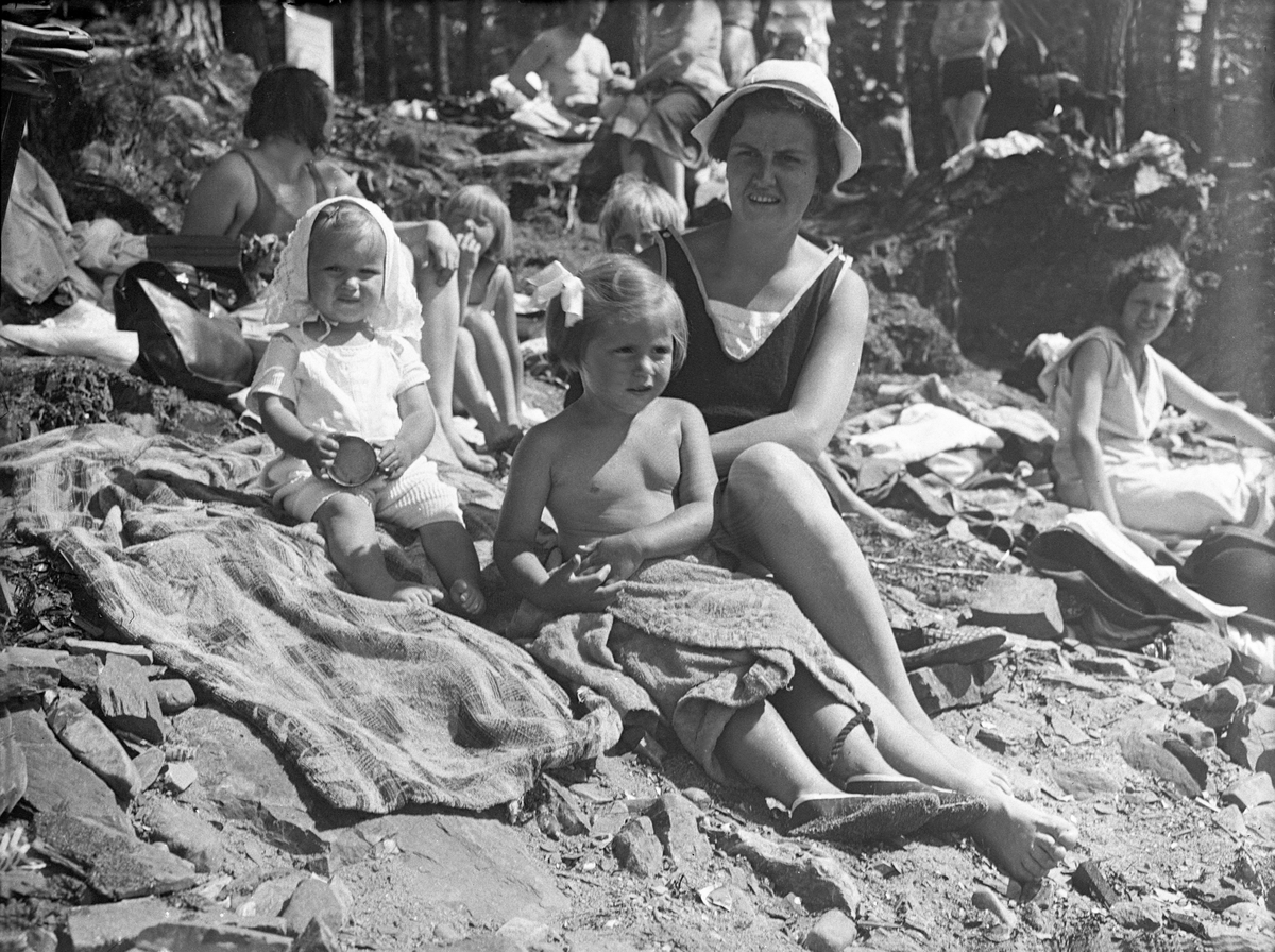 Søstrene Guri og Siri sitter sammen med sin mor Dordi Arentz på stranden i Paradisbukta, Bygdøy. Fotografert 1932.