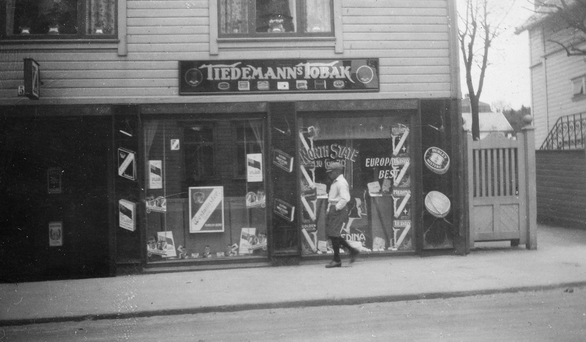 Gutt går på gaten utenfor tobakksforretning i Haugesund, 1932.