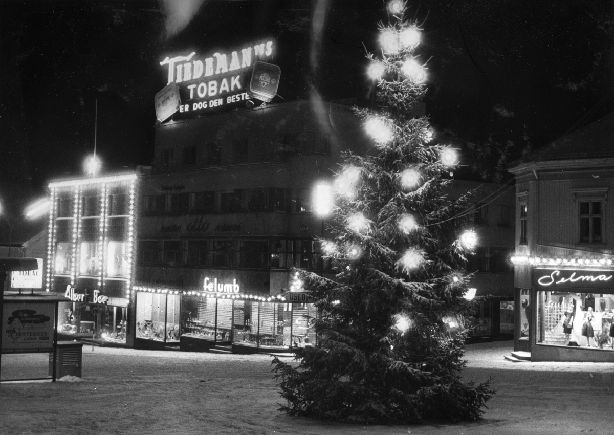 Gatebilde. Juletre med belysning. Lysende reklameskilt for Tiedemanns Tobaksfabrik.