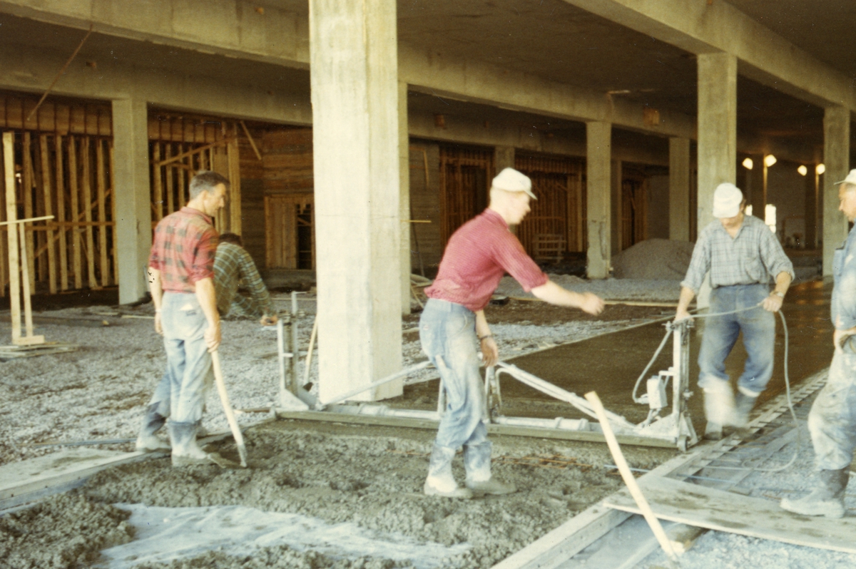 Byggeplass.
Konstruksjon av Tiedemanns Tobaksfabrik på Hovin i 1967. Bygningsarbeidere legger betonggulv inne i fabrikken.