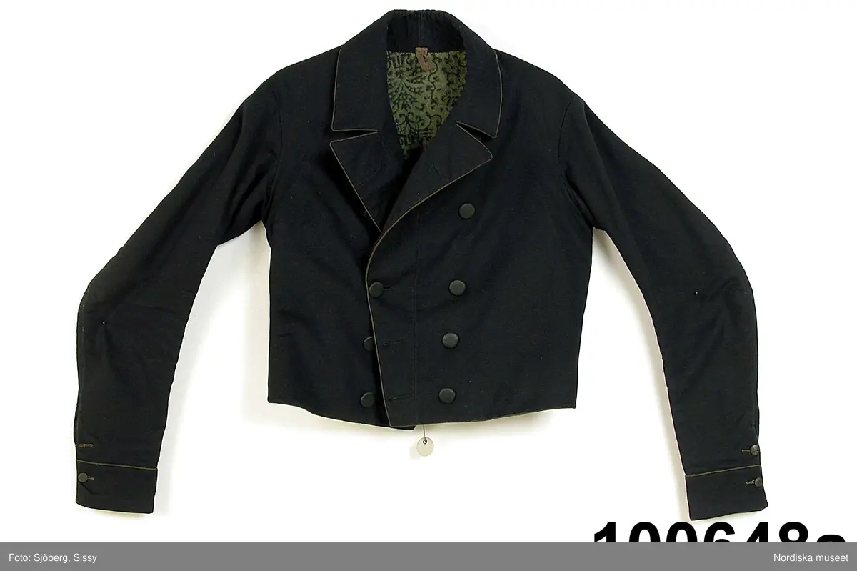 Huvudliggaren (år 1904-1905):
"100.648 a-c Brudgumsdräkt (1830-talet). Tröja, väst och byxor. Av mörkblått kläde. Tröjan och västen fodrade med ylle i grönt och svart, tryckt mönster, byxorna med 'smaik' lucka. Skåne Albo hd Andra-rums sn. Ink. 1904 2/9 Reimer P. L., skollärare, Järstorp, Lövestad. 10:- Bil. Reimer 9"