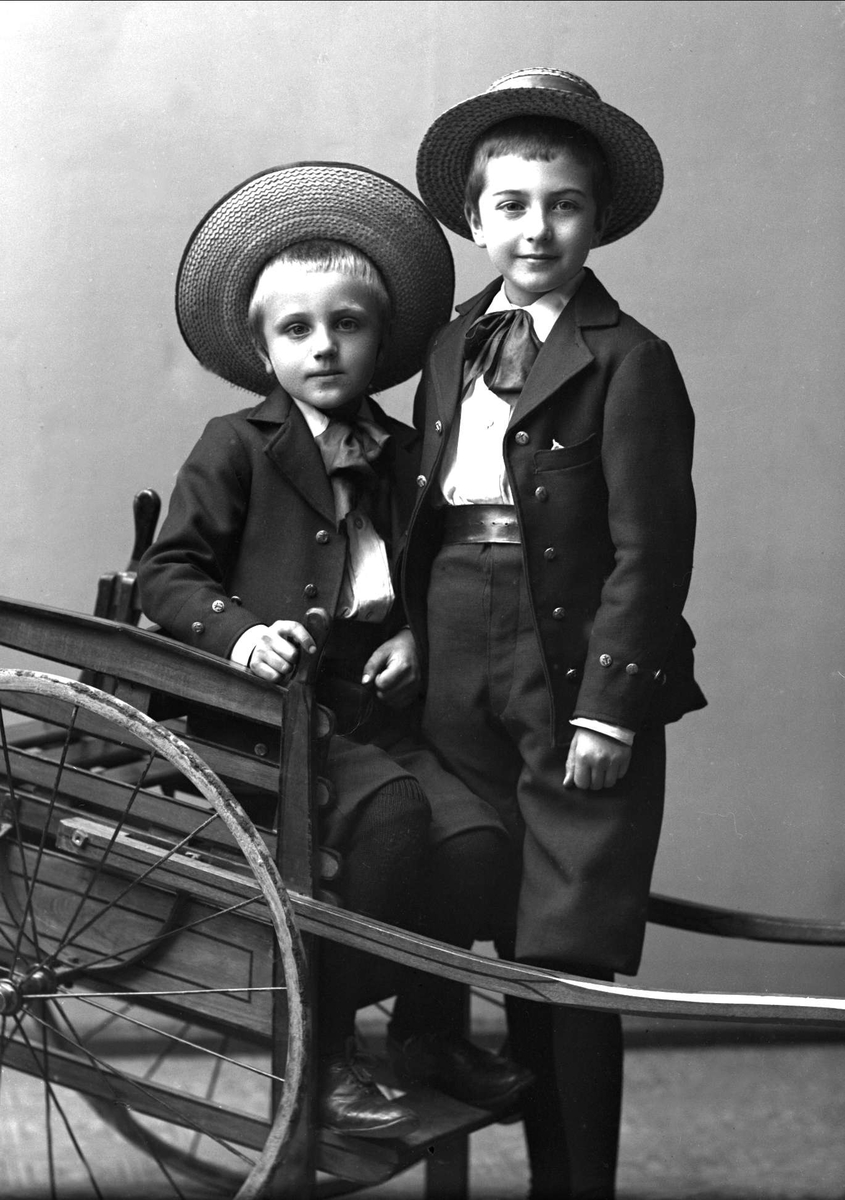 Gruppeportrett, to gutter med stråhatt ved drakjerre. Dr Hansons gruppe.