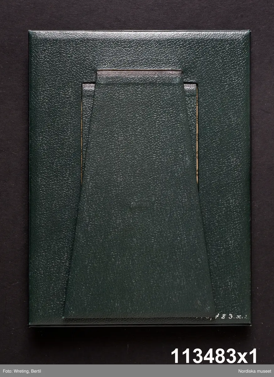 Huvudliggaren:
"a-å
Skrivbordsuppsats, 25 olika pjäser, däribland lampa, ljusstake m.m. allt ornerat med frimärksklipp. Jämte 4 mindre lådor med lösa frimärksdelar. Gåva 17/5 1909 av fru Augusta Cronholm f. Bratt, Birgerjarlsgatan 18, Stockholm."