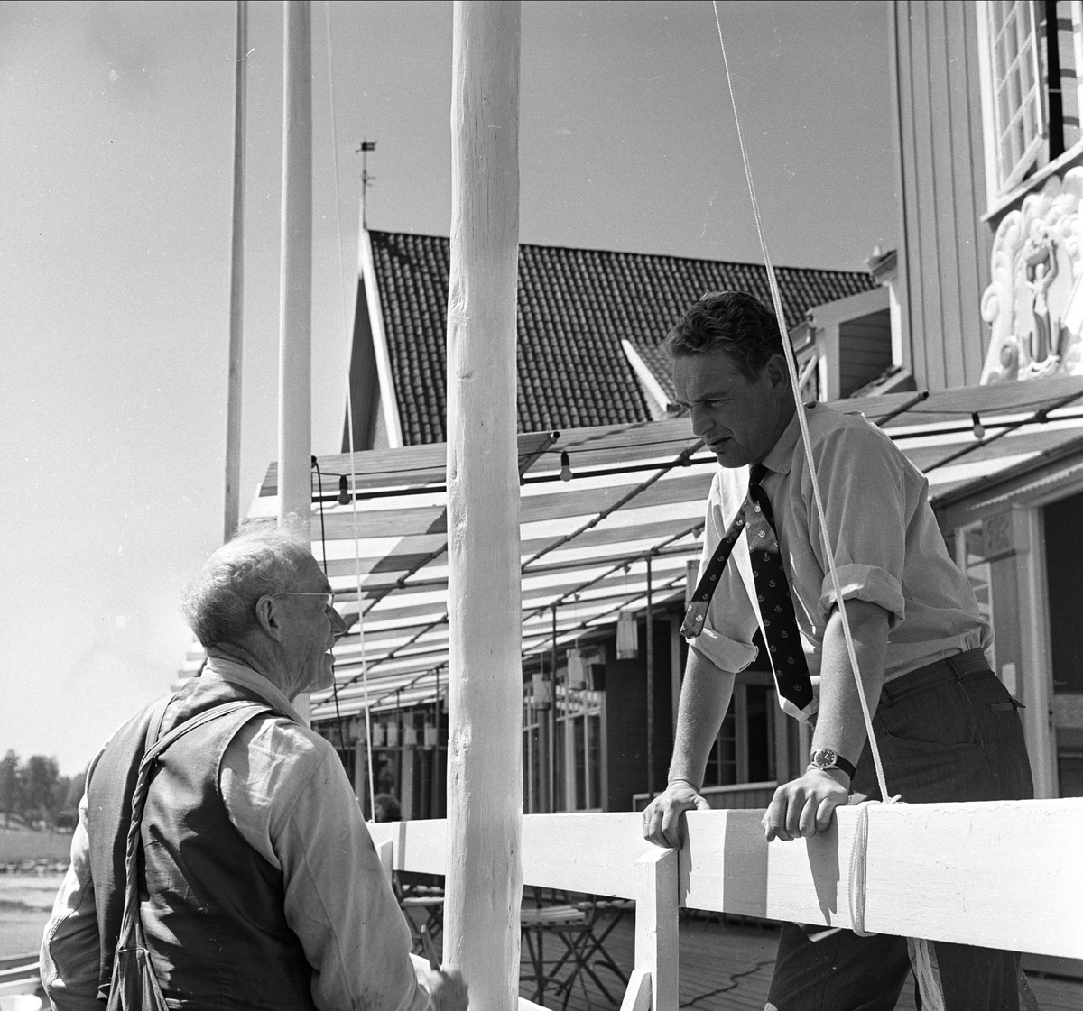 Stemning før regatta på Hankø, Fredrikstad, Østfold, juni 1964. To menn på brygge ved Seilerkroen.