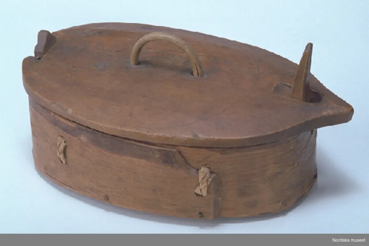 Inventering Sesam 1997-1998:
L 26, B 15, H 13 cm
Spånask, oval, svepäska. Botten, lock och svep av barrträ, utan fals. Svepet fästat med dymlingar av trä. Hopfästning av svepet med rottågor, två parallella snärjstygn.
Utskurna ståndare av lövträ, den ena fjädrande och överkragande, fästade med märlor av järn samt trädymlingar, genomgående vid botten.
Avtagbart lock med handtag av böjd träpinne borrat i skivan.
Svep, lock och ståndarknoppar betsade i brunt. Två ristade cirklar på locket. Bottenskiva av två brädor, ihopsatta med dymlingar av trä.
Tillhörde Seglora kyrka.
Agnetha Blomberg 1997