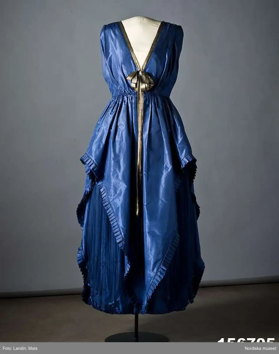 Ordered by Dora Lamm née Upmark (1880–1959), lady of the manor with a keen interest in innovative art and fashion. Delivered 1919.
A silk taffeta and pleated chiffon creation with gold ribbon details. Dora Lamm was married to the art collector Carl Robert Lamm of Näsby Manor, Täby. She embraced the Arts & Crafts movement and knew many artists such as Carl and Karin Larsson.