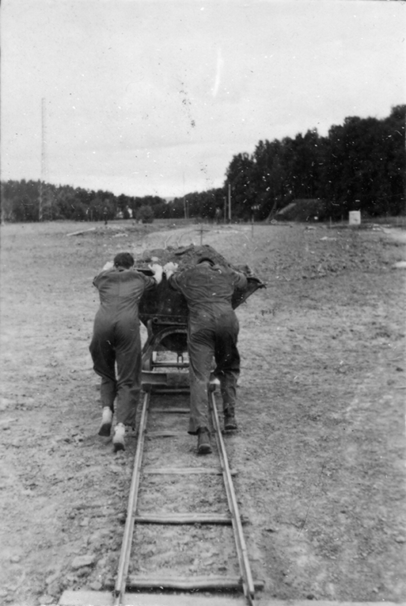 Idrottsplatsen på F 2 Roslagens flygflottilj byggs, 1943. Civilanställda tjänstemän i arbete med grävning.