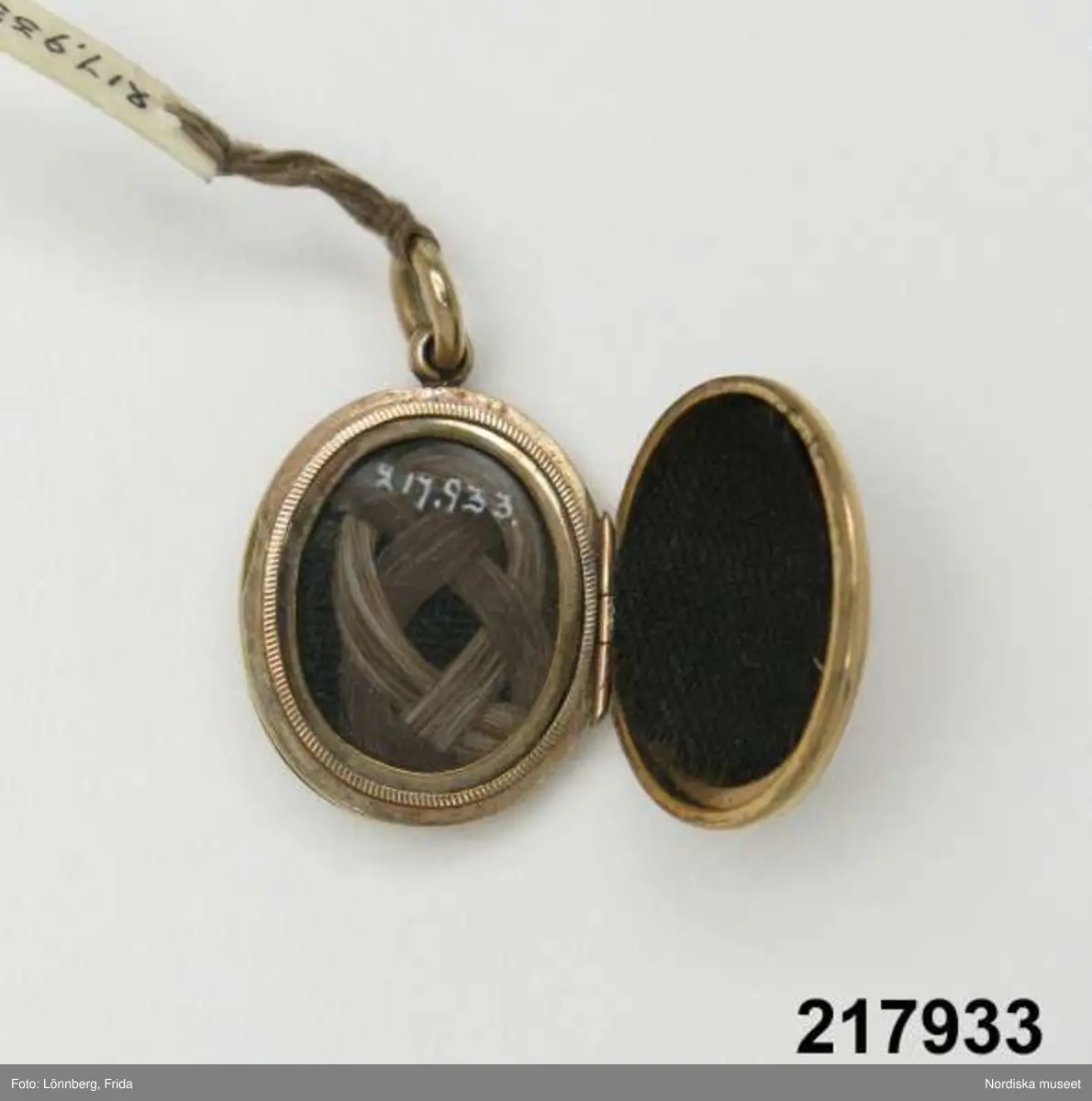 Katalogkort:
"Medaljong, guld med blå emalj,
H. 2,7 cm

Innehåller hårlock."