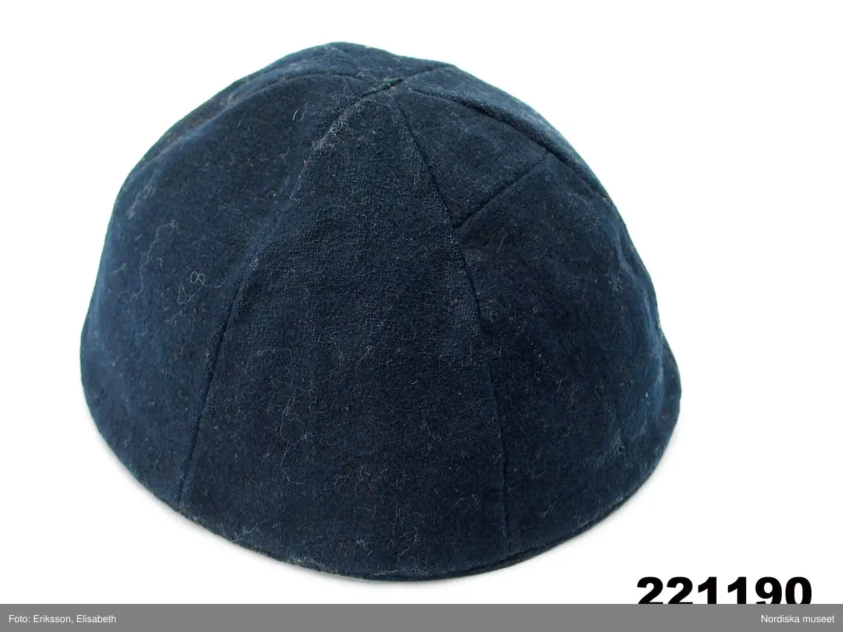 Mössa i kalottmodell sydd av 6 kilar i mörkblå vadmal kantad med samma tyg, fodrad med oblekt linnelärft.
Kallas för pickelhuva.
/Berit Eldvik juni 2006