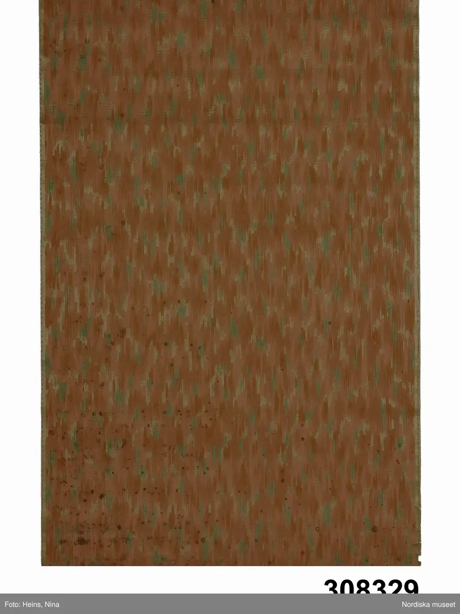 Huvudliggaren:
"Tapet, rulle, papper; maskintryck; brunaktig botten med fläckigt mönster i grönt och brunt; stpl "Emmaboda Tapetfabrik Arsenikfri". Br 50 cm, L ca 7 meter. från 1910-talet. Ytterligare 15 rullar finns (för användning)."
Katalogkort:
" C:a 7 m, 50 cm br.
Fläckartad grönt och brunt mönster mot brunaktig fond.
Lisa G. Mars 1969."

Anm: Invikt nedre kant.
/Cecilia Wallquist 2007-02-27.