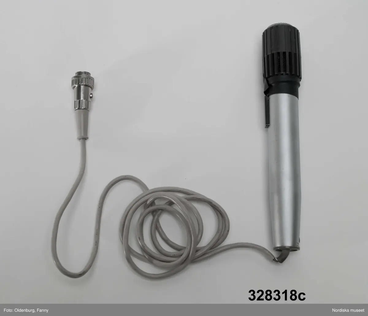 a-g:
Bärbar bandspelare för rullband. Metall, rektangulär, grå eloxerad, tangenter, vred på långsidan, fönster med ljudskala, varvräknare. Spole, mikrofon, mikrofonstativ, bruksanvisning. Batteri- och nätdriven, laddningsbar.
Tillhörande brun läderväska, axelväska med bred rem, ficka för bruksanvisning, mikrofonfack, konstmaterialfoder, uppknäppbar framsida, fällock med spännen. Adresslapp handskriven med förste intendet Göran Rosanders handstil.

a+) Bandspelare
b) Batteriladdare med sladd
c) Mikrofon med sladd
d) Mikrofonstöd
e) Intruktionsbok
f) Kopplingsschema (papper)
g+) Väska.

Den bärbara Uher-bandspelaren innebar en revolution för fältarbete. Fältarbetaren var inte enbart hänvisad till papper och penna. På 1970-talet fanns till en början endast en bärbar bandspelare. Fältarbeten planerades efter tillgänglighet till bandspelare. Samtliga avdelningar samsades till en början om dennna.
/Heidi Henriksson 2005-10-11