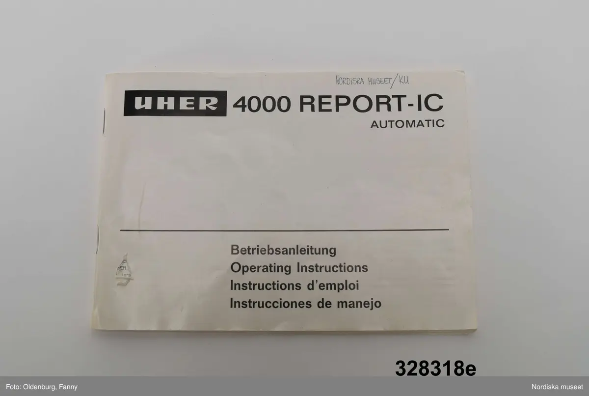 a-g:
Bärbar bandspelare för rullband. Metall, rektangulär, grå eloxerad, tangenter, vred på långsidan, fönster med ljudskala, varvräknare. Spole, mikrofon, mikrofonstativ, bruksanvisning. Batteri- och nätdriven, laddningsbar.
Tillhörande brun läderväska, axelväska med bred rem, ficka för bruksanvisning, mikrofonfack, konstmaterialfoder, uppknäppbar framsida, fällock med spännen. Adresslapp handskriven med förste intendet Göran Rosanders handstil.

a+) Bandspelare
b) Batteriladdare med sladd
c) Mikrofon med sladd
d) Mikrofonstöd
e) Intruktionsbok
f) Kopplingsschema (papper)
g+) Väska.

Den bärbara Uher-bandspelaren innebar en revolution för fältarbete. Fältarbetaren var inte enbart hänvisad till papper och penna. På 1970-talet fanns till en början endast en bärbar bandspelare. Fältarbeten planerades efter tillgänglighet till bandspelare. Samtliga avdelningar samsades till en början om dennna.
/Heidi Henriksson 2005-10-11