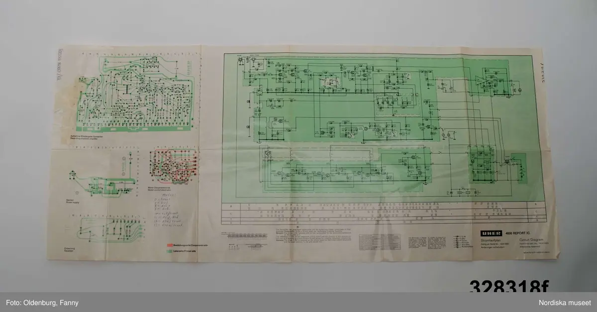 a-g:
Bärbar bandspelare för rullband. Metall, rektangulär, grå eloxerad, tangenter, vred på långsidan, fönster med ljudskala, varvräknare. Spole, mikrofon, mikrofonstativ, bruksanvisning. Batteri- och nätdriven, laddningsbar.
Tillhörande brun läderväska, axelväska med bred rem, ficka för bruksanvisning, mikrofonfack, konstmaterialfoder, uppknäppbar framsida, fällock med spännen. Adresslapp handskriven med förste intendet Göran Rosanders handstil.

a+) Bandspelare
b) Batteriladdare med sladd
c) Mikrofon med sladd
d) Mikrofonstöd
e) Intruktionsbok
f) Kopplingsschema (papper)
g+) Väska.

Den bärbara Uher-bandspelaren innebar en revolution för fältarbete. Fältarbetaren var inte enbart hänvisad till papper och penna. På 1970-talet fanns till en början endast en bärbar bandspelare. Fältarbeten planerades efter tillgänglighet till bandspelare. Samtliga avdelningar samsades till en början om dennna.
/Heidi Henriksson 2005-10-11