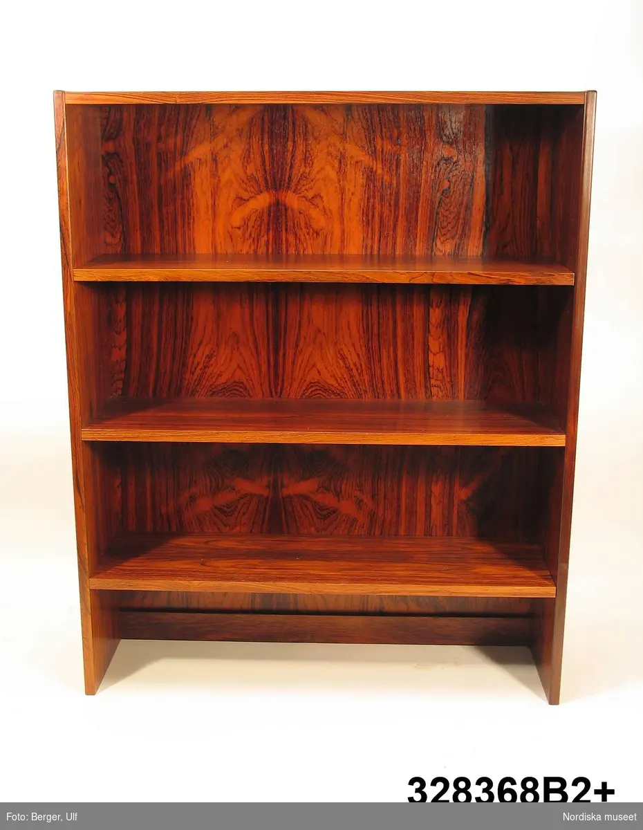 a-e:
Bokhylla, "Excellent",  med TV-bänk samt bar- och vitrinskåp, jakarandafaner på spånskiva, IKEA, 1968. 

Hyllan består av fyra sektioner med hyllor löst placerade på underredet. Skåp- och byråunderdelar med ryggar av masonit, fastnitade. Kvadratiska ben, fastskruvade i underredet. Lådsidor m.m. av björk och lådbottnar av vitlackerad masonit. Flyttbara hyllplan. Draghandtag och gångjärn av mässing.  Enligt IKEA-katalogen 1968 är ytan plastbehandlad.

Hyllan uppställd, från vänster till höger:
a:1+) Skåp med två dörrar samt a:2+) hyllöverdel, ett fast och två flyttbara hyllplan. Överst vitrindel med två skjutdörrar av glas (höjd 53,5 cm, bredd 41,5 cm).
b:1+) Byrå med tre lådor samt b:2+) hyllöverdel med tre flyttbara hyllplan. 
c:1+) Tv-bänk med en låda samt c:2+) hyllöverdel med tre flyttbara hyllplan.
d:1+) Skåp med två dörrar samt d:2+) hyllöverdel med 1 flyttbart hyllplan. Överst vitrindel med två skjutdörrar av glas (höjd 53,5 cm, bredd 41,5 cm), därunder ett barskåp med spegel som bakvägg, utrymme för flaskor till vänster och två glashyllor (48 x 19,5 cm) till höger. Barskåpet med fällbar klaff med lås. Belysning monterad i skåpets överkant.
e) Nyckel till barskåpets klaff. L 4,3 cm.

Möbeln har använts av givarinnan, Berith Helldén, f. 1945, hemmafru, och hennes man, Lars-Göran Helldén, f. 1946, inköpare, Tungelsta. Paret gifte sig 1967 och bodde som nygifta i en liten lägenhet i Borås. När de fick möjlighet att flytta till en större lägenhet i samma stad, utökades vardagsrumsmöblemanget. Hyllan inköptes 1968 på IKEA i Älmhult. Enligt IKEA-katalogen 1968 kostade de fyra hyllsektionerna totalt 2484 kronor. Hyllan har använts som förvaringsmöbel i vardagsrummet i Borås och i familjens nuvarande bostad i Tungelsta fram till våren 2005, då den inköptes av museet.

Hyllans innehåll har dokumenterats och en utförlig intervju med Berith Helldén har gjorts 2005-05-09 (se arkivreferens).
/Anna Womack 2005-10-18
