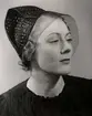 Hattmode visas på varuhuset  Nordiska Kompaniet i Stockholm 1936.
En ung kvinna poserar i halvprofil iförd en liten hatt av präglat skinn, möjligen krokodil. Hatten har ett litet, finmaskigt flor.