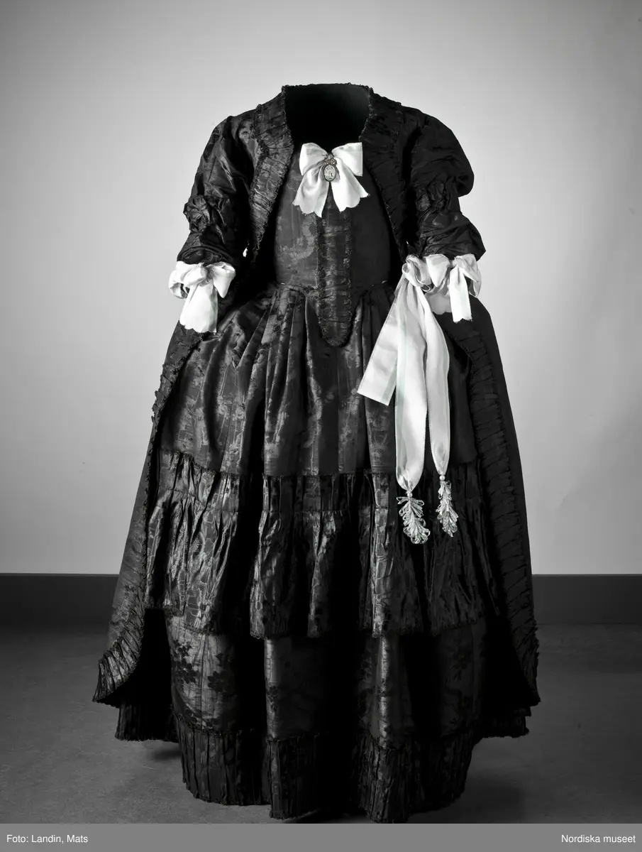Bruddräkt, svenska dräkten. Av svart mönstrat siden. Buren 1 januari 1780 av Sofia Lovisa Brüch. Nordiska museet inv nr 192119.