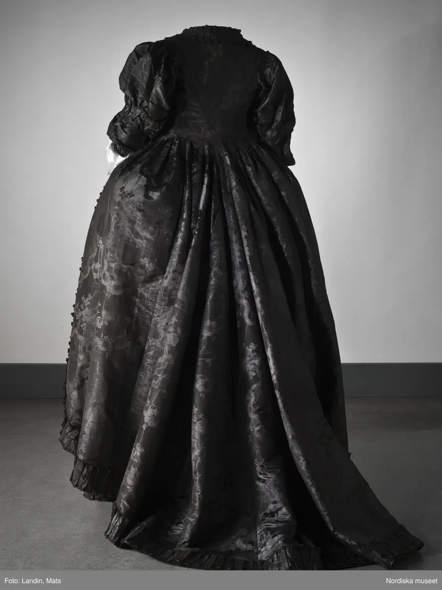 Bruddräkt, svenska dräkten. Av svart mönstrat siden. Buren 1 januari 1780 av Sofia Lovisa Brüch. Nordiska museet inv nr 192119.