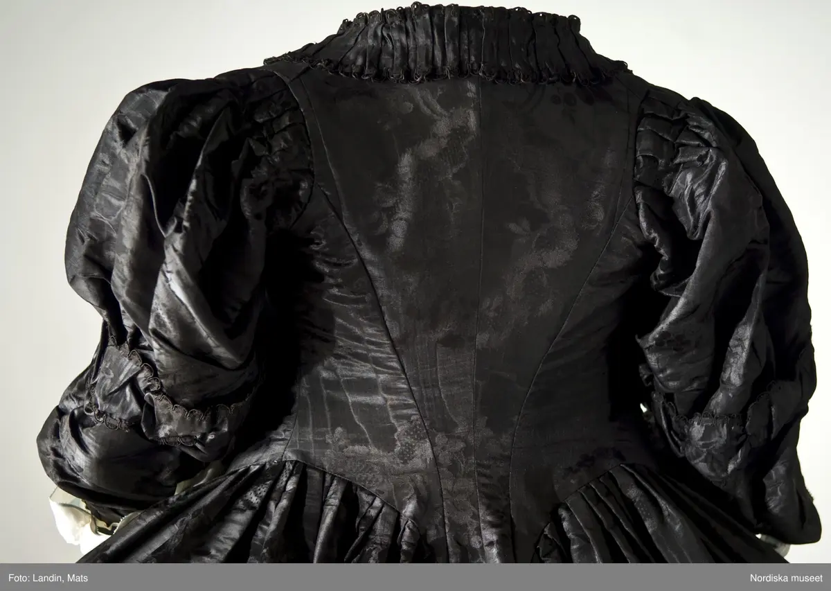 Bruddräkt, svenska dräkten. Av svart mönstrat siden. Buren 1 januari 1780 av Sofia Lovisa Brüch. Nordiska museet inv nr 192119.