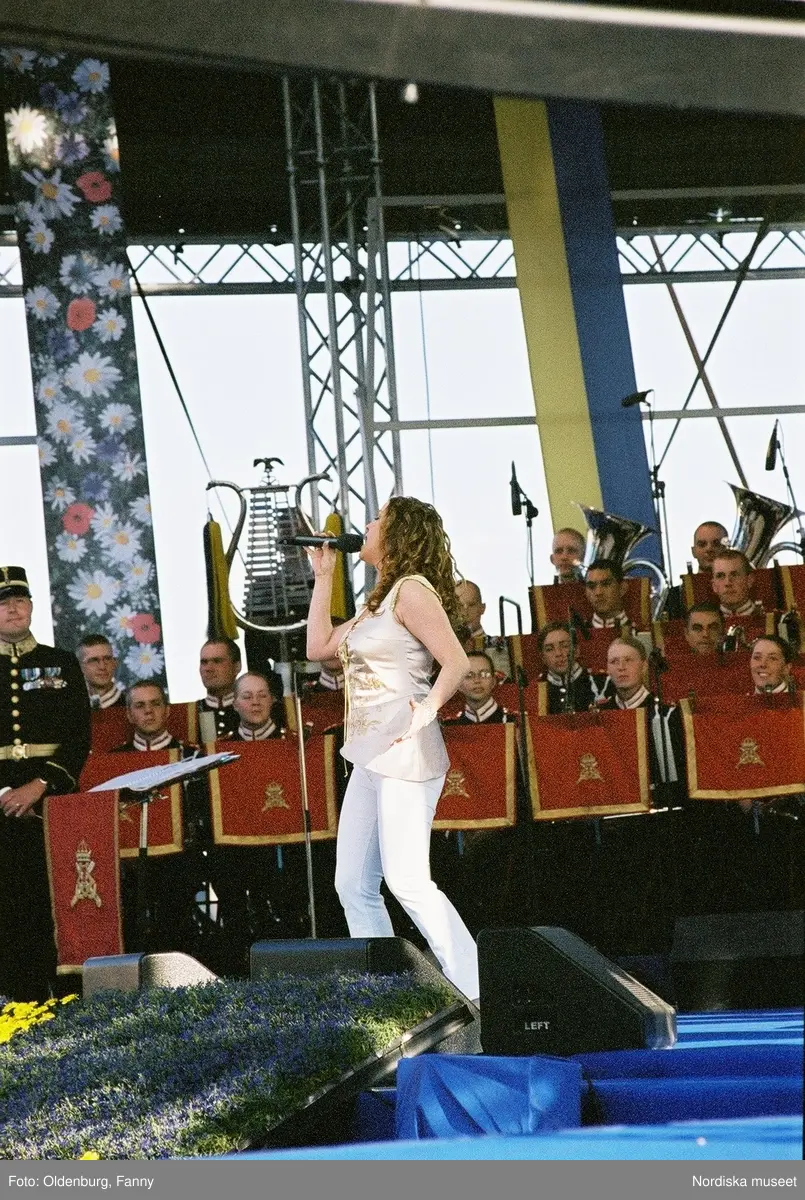 Firandet av den svenska nationaldagen den 6 juni 2004 på Skansen, Stockholm. Den kungliga familjen. Orkester. Publik. Artisterna Shirley Clamp, Tomas Ledin och Lasse Berghagen. Programledaren Agneta Bolme Börjefors.