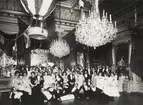 Gruppbild. Troligen föreningsfest hållen 1897 i samband med Andrées ballongfärd till Nordpolen. I bakgrunden anas ett plakat med balens dansordning. I taket hänger en modell av en luftballong.