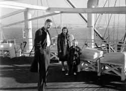 En man i överrock, en kvinna och en flicka, båda iklädda päl