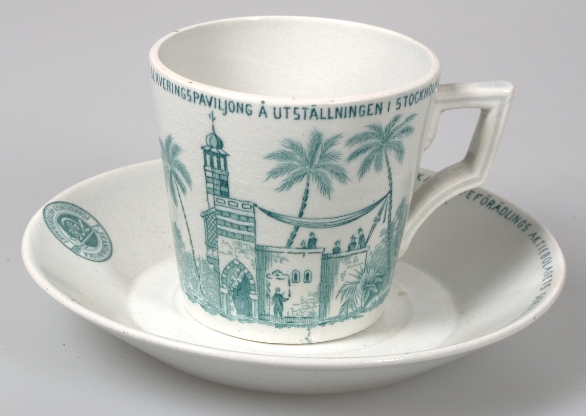 Kaffekopp med fat, vitglaserade med grön dekor. Runt kanten: "Minne från skandinaviska kaffeförädlings aktiebolags serveringspaviljong å utställningen i Stockholm 1897". Samma text på fatet. Grön tryckt stämpel: "GUSTAFSBERG".