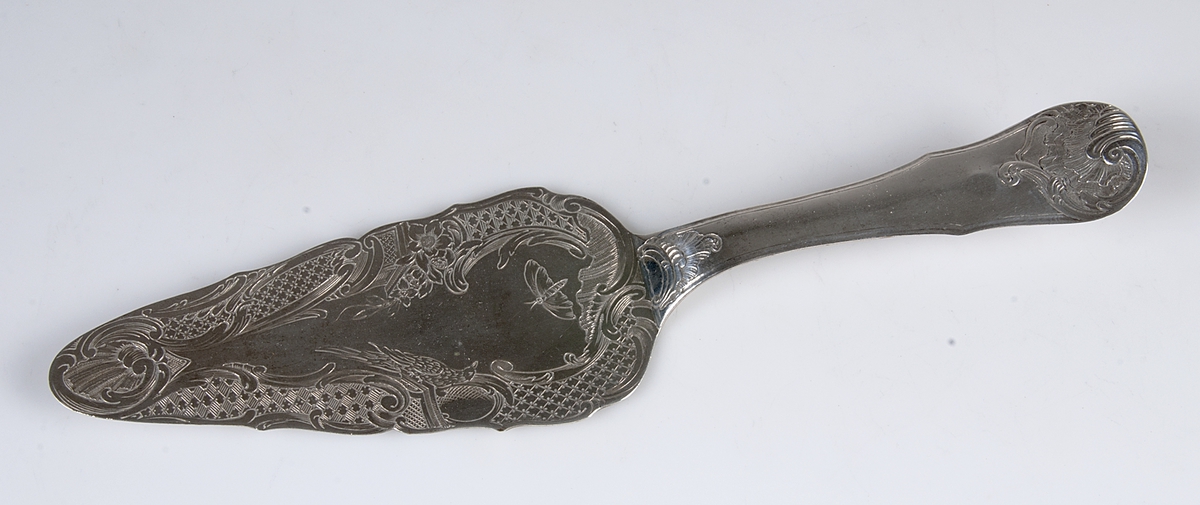 Tårtspade av silver. Graverat: MD (MD står för Matthias Dubois). Stämplar: B, tre kronor, St Erik, LAMPA. Stämplad: JC.