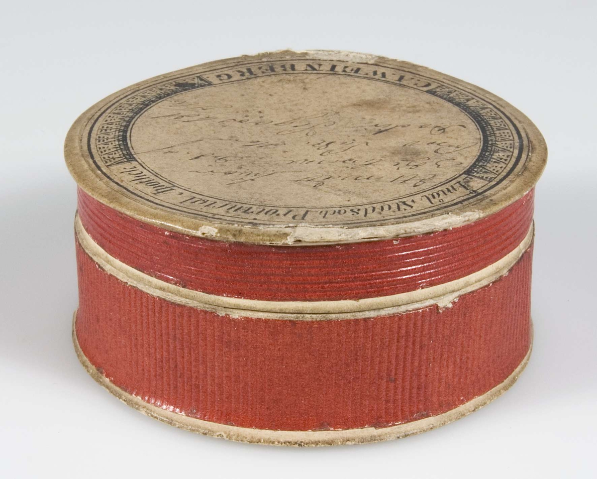 Ask av papp, röda sidor. Vit etikett med svart text "Åmål stads och Provincial Apotek C. A. Weinberg", med bläck "Ett mått hvar 3 dje timme, Ord. af Prov. Las. Herr Doktorn Segerstedt".

